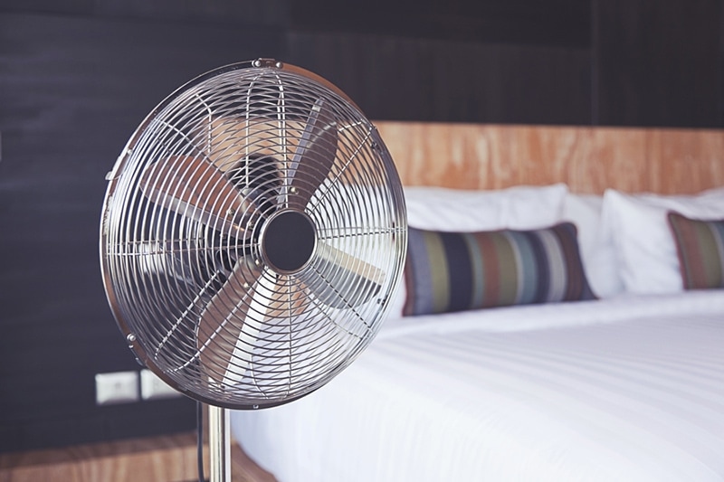 Old electric fan near the bed in the room, improve your home's indoor air quality