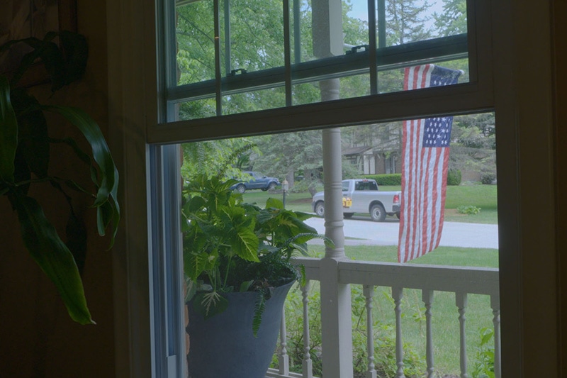 Video - Energy Saving Tip 6. Person approaching window with American flag in front lawn.
