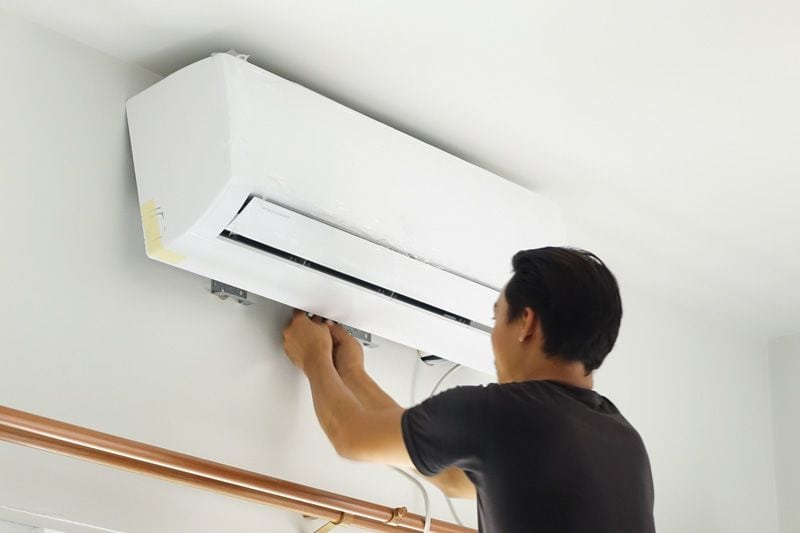 Image of someone fiddling with ductless system. Video - Choose a Ductless System for Your Home Remodel.